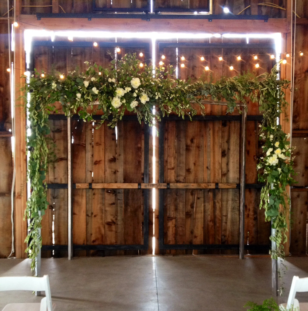 Large foliage and floral arch for a wedding in a barn by Gorgeous and Green